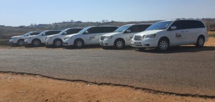 The image shows six white cars belonging to Ithemba Elitjha Funeral services parked on the side of a road in Mpumalanga. They are branded with the Ithemba Elitjha magnetic stickers