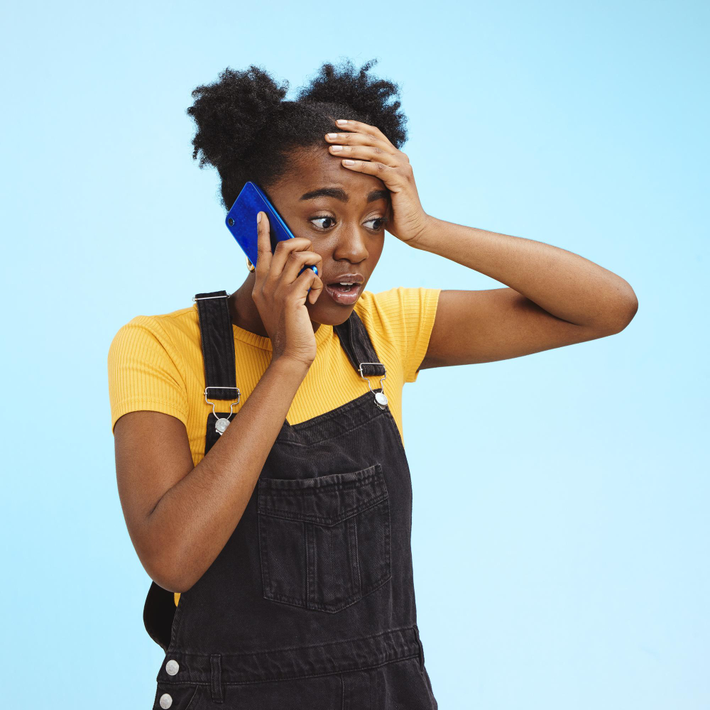 An African American young lady speaking on a phone with looking like she's hearing bad news